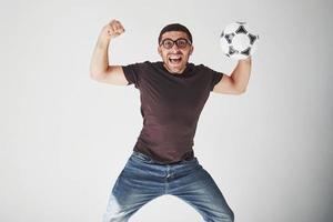 Aficionado al fútbol emocionado con un balón de fútbol aislado sobre fondo blanco. salta es feliz y realiza varios trucos de animar a su equipo favorito foto