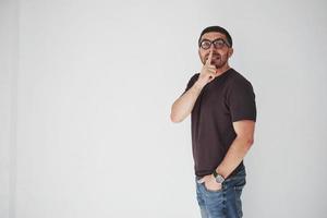 Young casual man over white background wall asking to be quiet with finger on lips. Silence and secret concept photo