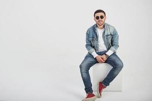 Young hipster guy wearing glasses laughing happily isolated on white background photo
