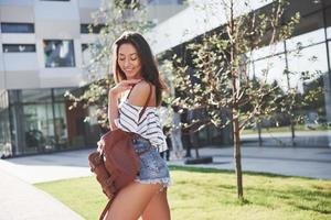 hermosa y feliz joven estudiante con mochila cerca del campus de la universidad. concepto de educación y ocio foto