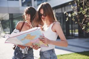 Two female tourist with map visiting a new city and is looking for a way to the hotel photo