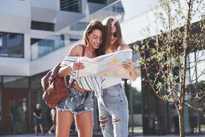 Two female tourist with map visiting a new city and is looking for a way to the hotel photo