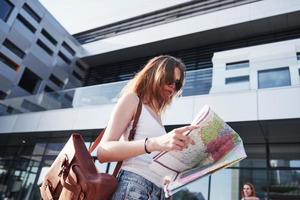 Female tourist with map visiting a new city and is looking for a way to the hotel