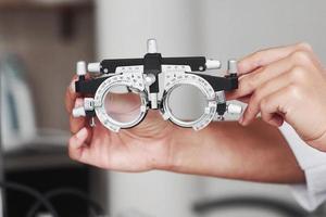 Focused photo. Female hands holding the optical device for eye testing photo