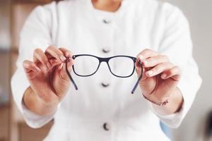 Front view. Woman hands holds the blue eyeglasses in the doctor cabinet photo