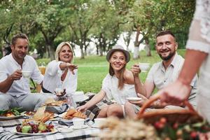 People look at woman. Group of adult friends have a rest and conversation in the backyard of restaurant at dinner time photo