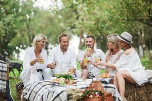 Someone said good joke. Adult friends drink orange juice and smiling. Outdoor part of restaurant photo