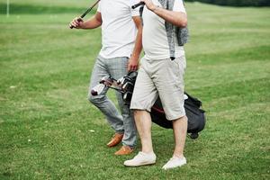 Foto recortada de dos amigos en el campo de deportes con equipo de golf