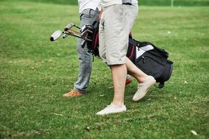 caminando hacia el destino. Foto recortada de dos amigos en el campo de deportes con equipo de golf