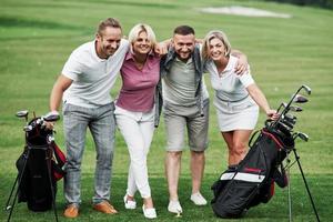 Photo of friends hugging and smiling with golf equipment after the game