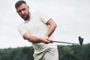 Focused look. Portrait of golf player in the lawn and stick in hand