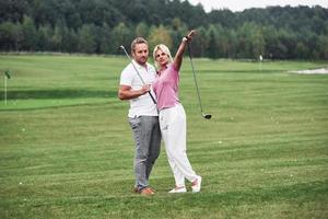 Woman wants to go on other side. Couple of golf players with sticks in their hands standing on the lawn
