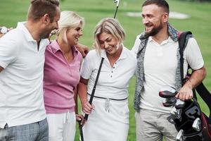 Hugs and close up look. Cheerful friends spending time in the golf field with sticks and good mood photo