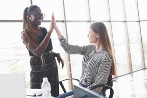 High five. Two multiracial women are satisfied about the document that they made photo