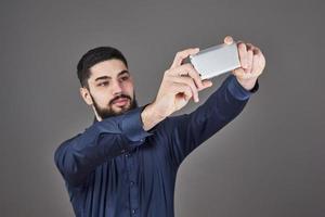 Happy smiling handsome bearded young man making selfie photo