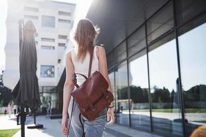 Beautiful, happy young student girl with backpack near the campus of university. Education and leisure concept photo