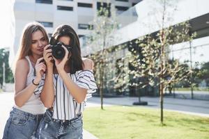 Two pretty pretty friends of the girl with the camera take photos together and walk in the city