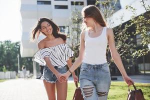 Two beautiful happy young student girl with backpack near the campus of university. Education and leisure concept photo