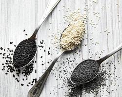 Black and white sesame seeds and poppy seeds in a spoons