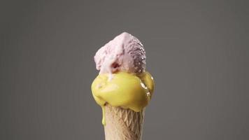 Yellow and pink Ice cream cone gradually melting on isolated background. Sugar concept. Time lapse video
