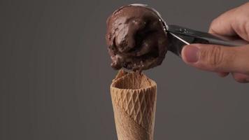 una persona que sirve un delicioso helado de chocolate en un cono de galleta. concepto de dulce y azúcar. video