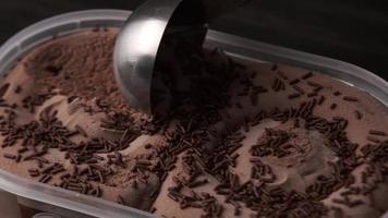 vue rapprochée d'une personne en train de ramasser de la crème glacée au chocolat dans un bac. video