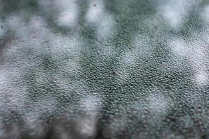 Melting small pieces of ice on the window glass in the form of scales. Abstract background. photo