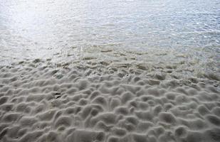 Wave textured sand shapes on low tide photo