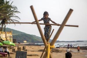 anjuna, india, 14 de octubre de 2015 - niña de goa no identificada en la cuerda floja en la playa de anjuna. foto