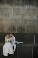 Joven pareja de recién casados sentados en una pared de bloques foto