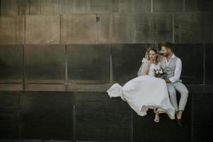 Young newlywed couple sitting on a blocky wall photo