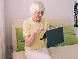senior cheerful caucasian stylish woman with gray hair with her tablet at home. Technology, emotions, family, healthy lifestyle, positive thinking concept photo