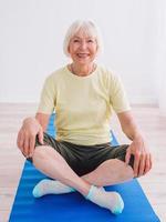 senior woman doing yoga online indoor. Anti age, sport, technology, yoga concept photo