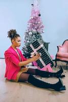 sad afro american woman by the Christmas tree disappointed by christmas present. Christmas, new year, frustration, happiness, holidays concept photo