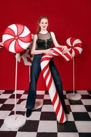 Bella pelirroja mujer bonita con enormes caramelos de caña en adornos navideños foto