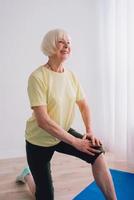 senior woman doing yoga online indoor. Anti age, sport, technology, yoga concept photo