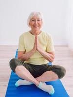 senior woman doing yoga online indoor. Anti age, sport, technology, yoga concept photo