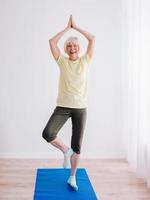 mujer mayor haciendo yoga en el interior. anti edad, deporte, concepto de yoga foto