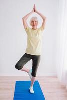 mujer mayor haciendo yoga en el interior. anti edad, deporte, concepto de yoga foto