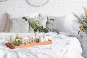 hermoso interior de la casa con tonos blancos y beige, con atrapasueños, flores secas y una cama foto