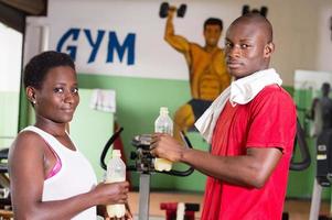 Young woman and her trainer hold bottles of fruit juice in hand. photo