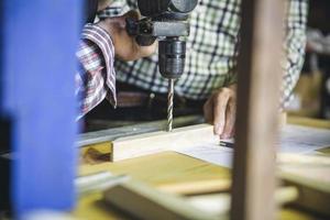 Pareja irreconocible perforando un listón de madera foto