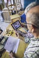 Senior couple in a carpentry looking tablet
