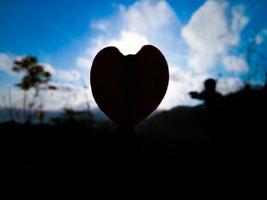 Silhouette of the heart shape on Blue sky background photo