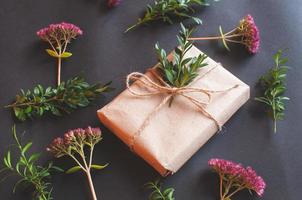 Caja de regalo artesanal con nudo natural con florecitas rosadas sobre fondo negro foto