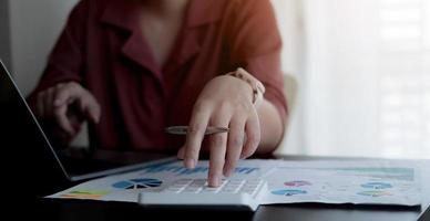 Close up Business woman using calculator and laptop for do math finance on wooden desk in office and business working background, tax, accounting, statistics and analytic research concept photo