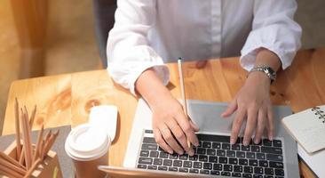 Cerca de las manos de la chica estudiante comparando notas en tableta digital sentado en un escritorio. mujer usando tableta en el café. concepto de finanzas empresariales. foto