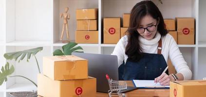 Young start up small business owner writing address on cardboard box at workplace.small business entrepreneur SME , working with box at home, Online selling, e-commerce, packing concept