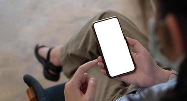 Imagen de maqueta en blanco teléfono celular con pantalla blanca. Mano de mujer sosteniendo mensajes de texto usando el móvil en el escritorio en la oficina en casa. foto