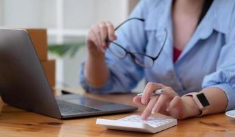 Close up Business woman using calculator and laptop for do math finance on wooden desk in office and business working background, tax, accounting, statistics and analytic research concept photo